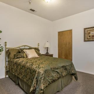 A cozy bedroom with green bedding and simple decor.