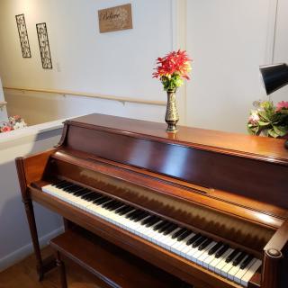 A wooden piano adorned with a vase of flowers in a living room setting.
