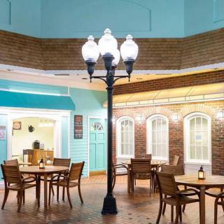 An indoor cafe setting with wooden tables and chairs, illuminated by a vintage-style lamp post.