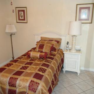 A cozy bedroom with a neatly made single bed, a nightstand, and decorative elements.