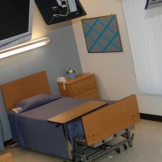 A hospital room with a single bed and medical equipment.