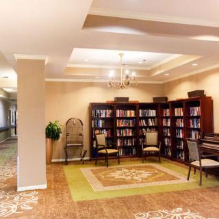 A cozy library with bookshelves, chairs, and a carpeted reading area.