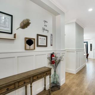 A modern hallway featuring a console table, wall art, and light wood flooring.