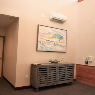 A room interior featuring a modern cabinet, a wall-mounted painting, and an air conditioning unit.