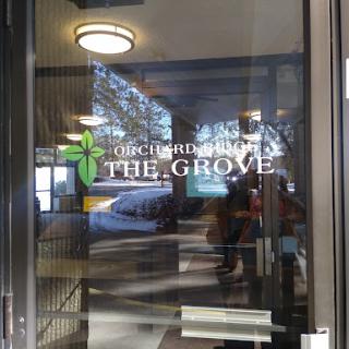 Entrance to The Grove, featuring a prominent glass door and signage.