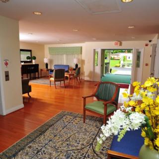 A cozy living area with wooden flooring, comfortable seating, and a decorative arrangement of flowers.
