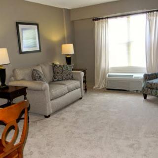 A cozy living room with a sofa, chairs, and ambient lighting from two lamps.