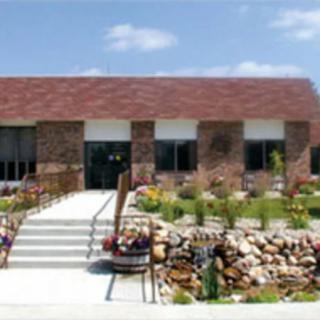 A brick building surrounded by a landscaped garden with a pathway leading to the entrance.