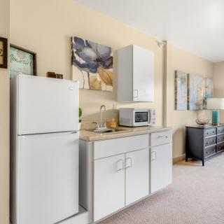 An apartment kitchen with a fridge, microwave, and cabinets, decorated with artwork on the walls.