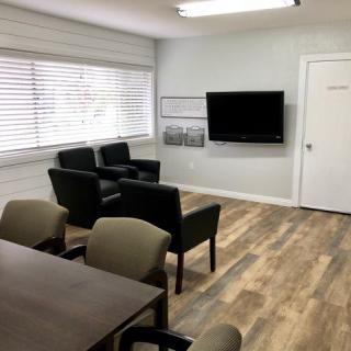A modern conference room with seating, a wall-mounted television, and wood flooring.