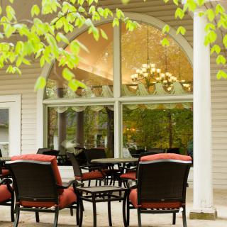 An inviting patio with comfortable seating and a view of large windows framed by greenery.