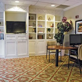 A cozy office space with a computer desk, shelving units, and a television.