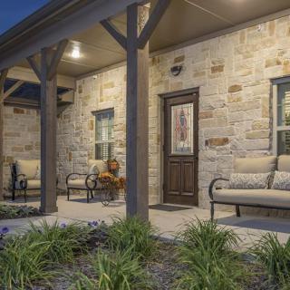 A cozy porch with comfortable seating against a stone exterior in the evening.