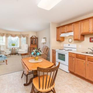A cozy kitchen and dining area connected to a living room with wooden furniture and cabinetry.