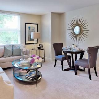 A cozy living room with modern decor, featuring a sofa, coffee table, and a small dining area.
