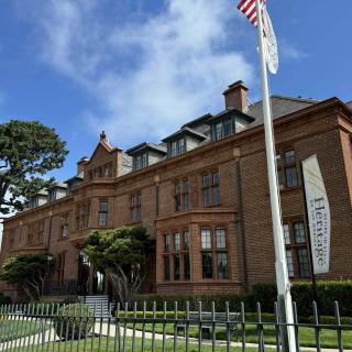 A historic building with a museum banner and an American flag in front, set against a clear blue sky.