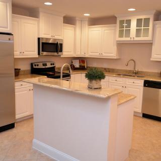 Modern kitchen with white cabinets and stainless steel appliances.