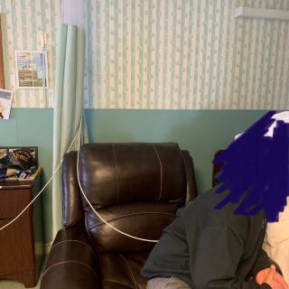 A hospital room with an IV setup and a recliner chair.