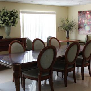 A well-furnished dining room featuring a wooden table and elegant chairs, complemented by decorative plants.
