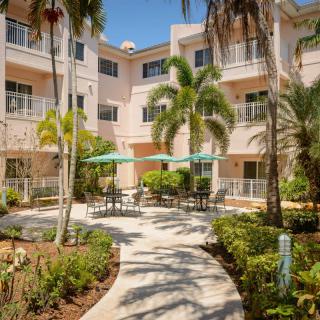 A sunny courtyard of an apartment complex with palm trees and outdoor seating.