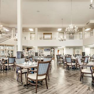 Spacious dining area with elegant chandeliers and neatly arranged tables and chairs.