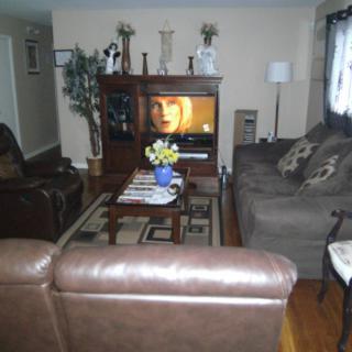 A cozy living room with a television, couches, and a coffee table decorated with flowers.