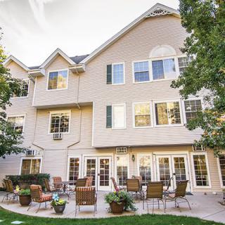 A view of a residential building with a spacious patio area, surrounded by trees.