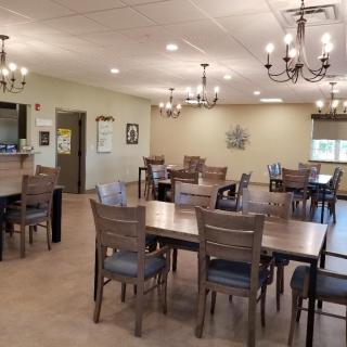 A spacious dining room featuring wooden tables and chairs, illuminated by elegant chandeliers.