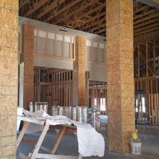 An interior view of an unfinished construction site featuring exposed wooden beams and framework.