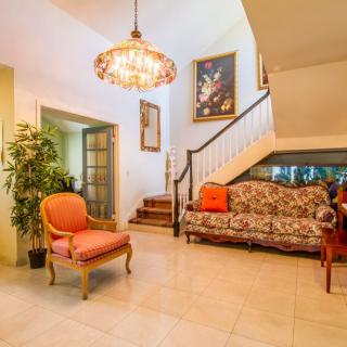 A cozy living room with elegant furniture, a chandelier, and decorative wall art.