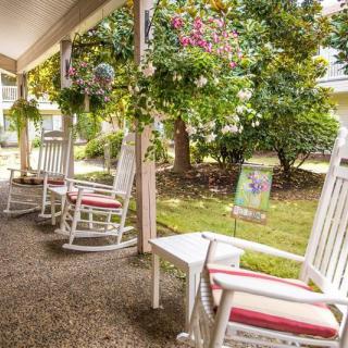 A cozy porch with white rocking chairs overlooking a lush garden filled with flowers and greenery.