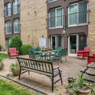 A cozy outdoor patio area with garden furniture and plants outside an apartment building.