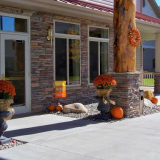 A beautifully decorated home entrance showcasing autumn decor with pumpkins and flowers.