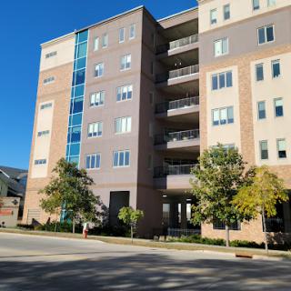 A modern multi-story apartment building with a mix of brick and glass facades.