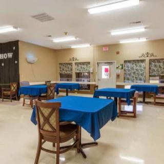 A spacious community room featuring tables with blue tablecloths, suitable for gatherings and activities.