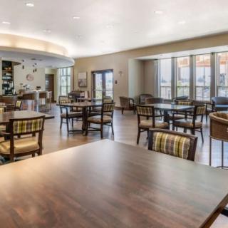 A spacious and modern dining area with tables and chairs, featuring large windows for natural light.