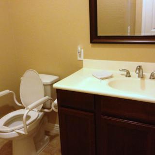 A clean and accessible bathroom with a toilet, sink, and mirror.