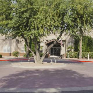A building entrance surrounded by trees and landscaping.