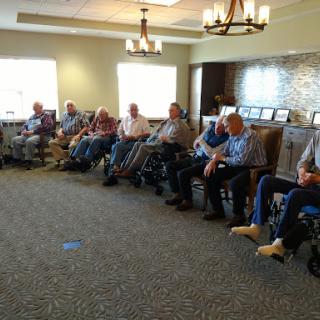 A group of elderly individuals seated together in a community center, engaging in conversation.