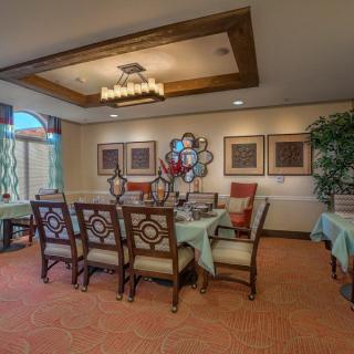 A well-decorated dining room featuring an elegant table and chairs, complemented by a chandelier and wall artwork.