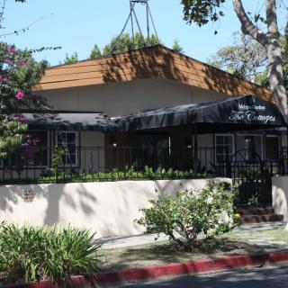 Exterior view of a restaurant with an awning and surrounding trees.