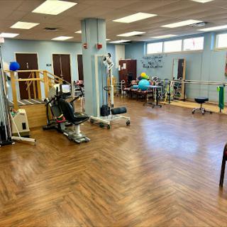 A spacious physical therapy center equipped with various exercise machines and tools for rehabilitation.