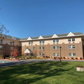 A brick apartment building with a neatly manicured lawn on a sunny day.
