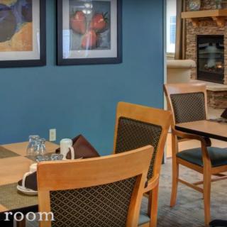 Cozy dining room with wooden tables and chairs, adorned with artwork on the walls.