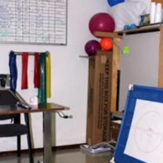 A physiotherapy office with a desk, whiteboard, and various exercise equipment.