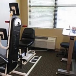A compact workout area featuring gym equipment and an office desk.