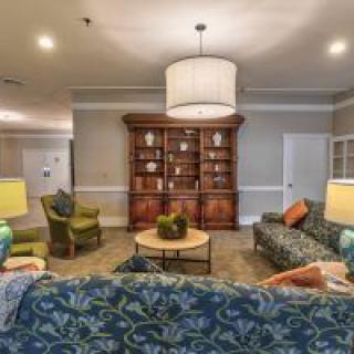 Cozy living room with patterned sofas, chairs, and a wooden cabinet.