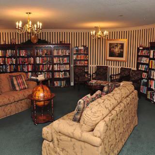 A cozy library room with bookshelves, comfortable sofas, and elegant chandeliers.