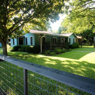A cozy house surrounded by lush greenery and a well-maintained lawn.