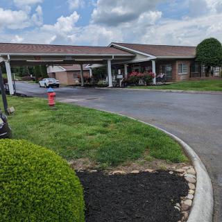 A building with a covered entrance and landscaped surroundings on a cloudy day.